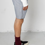 Person wearing light blue shorts, a white shirt, black shoes, and maroon socks on a plain background