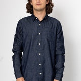 Man wearing denim shirt in front of a grey background