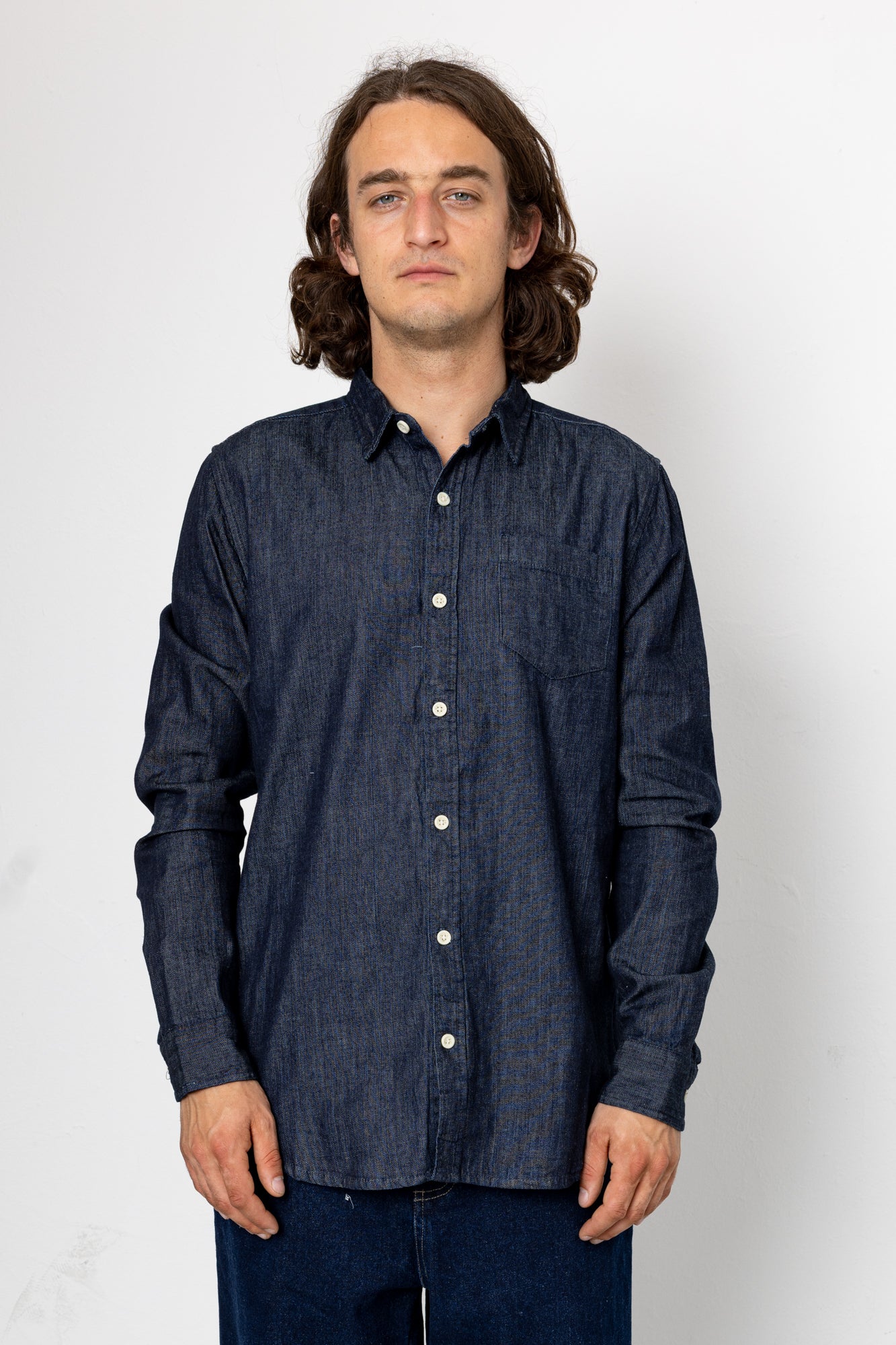 Man wearing denim shirt in front of a grey background