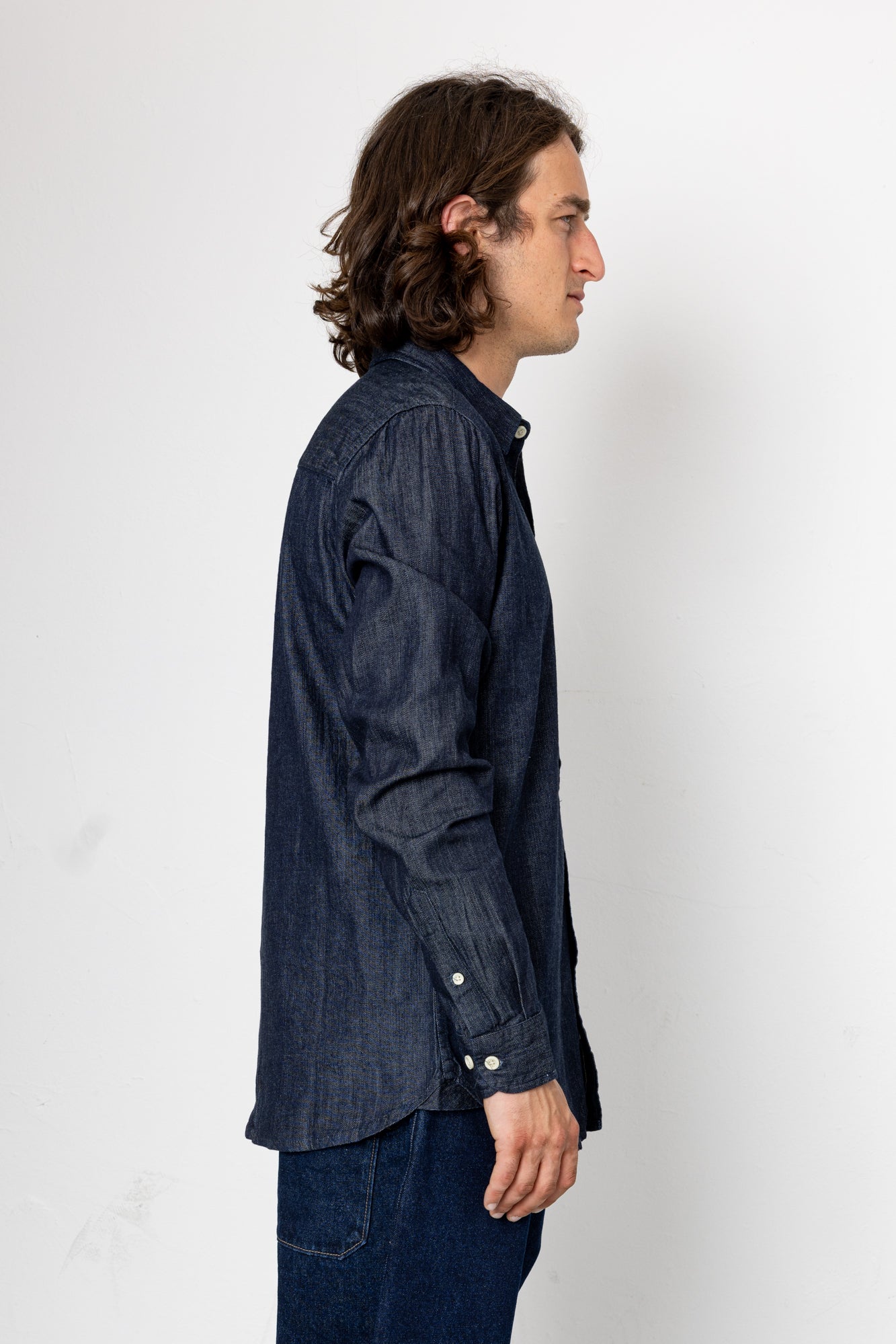 Man wearing a dark denim shirt against a white background