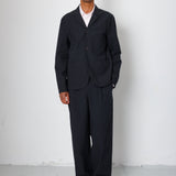 Man wearing a black suit standing against a white background