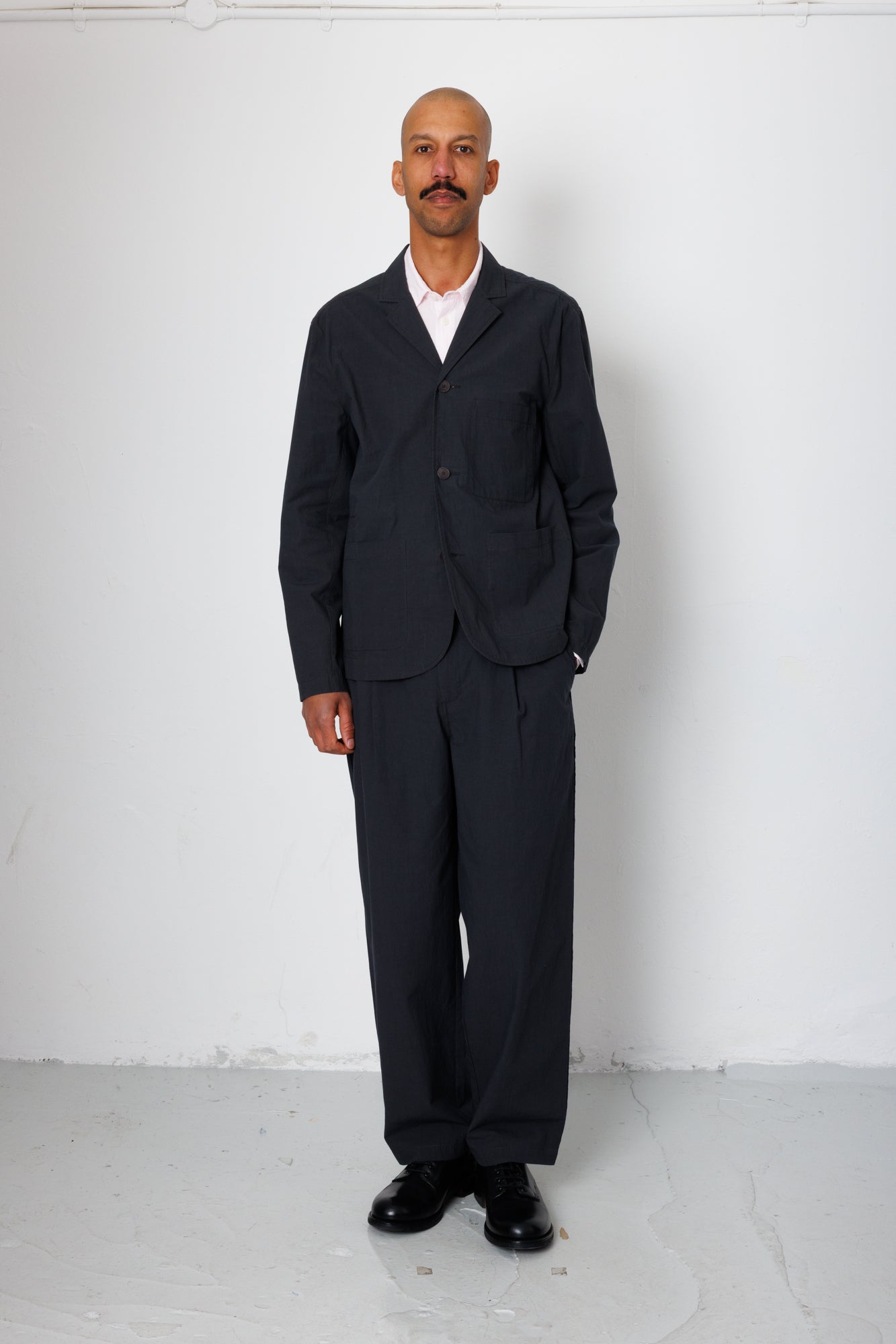 Man wearing a black suit standing against a white background
