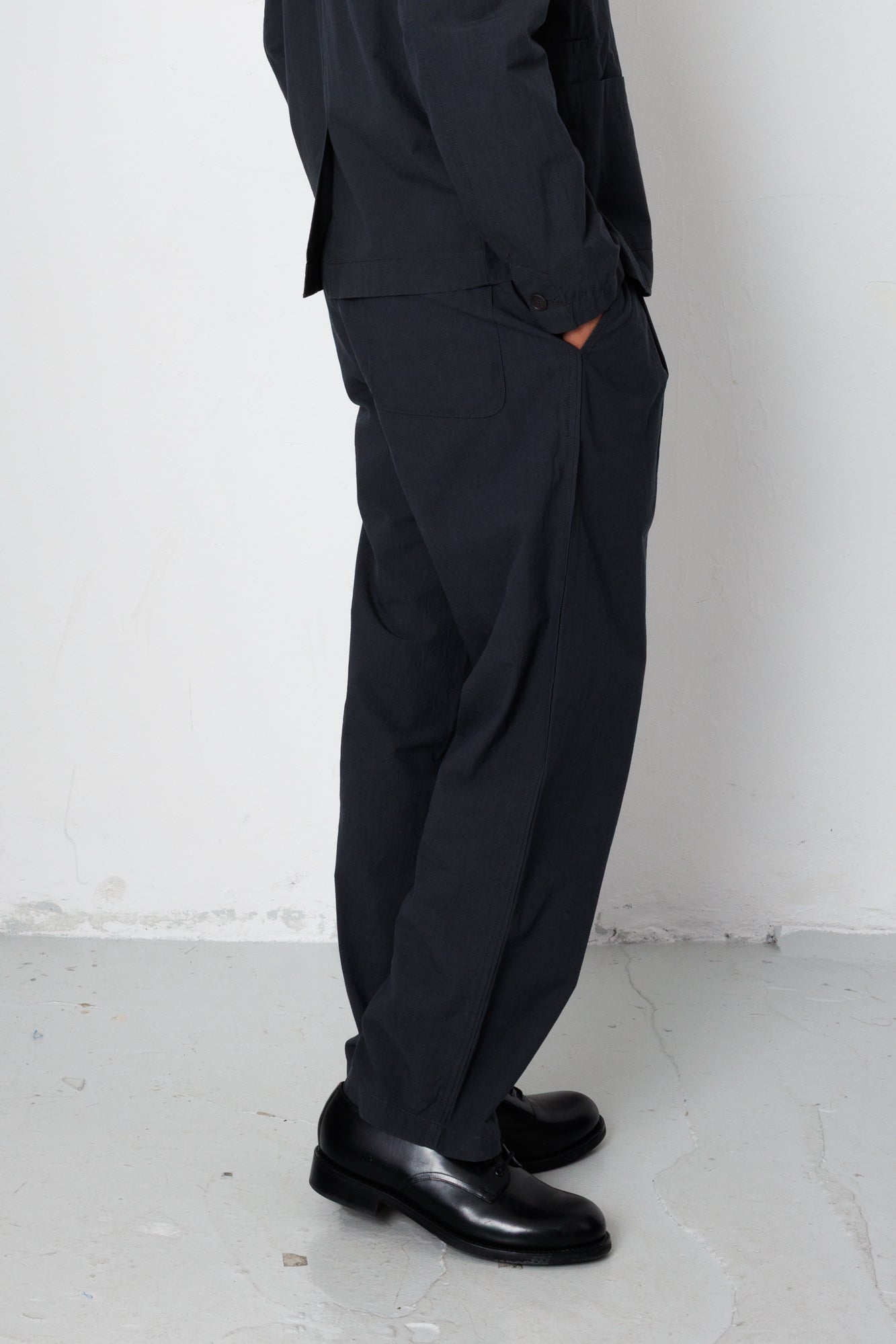 Person wearing a black outfit with wide-leg pants against a white background