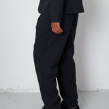 Person wearing a black suit and shoes against a white background