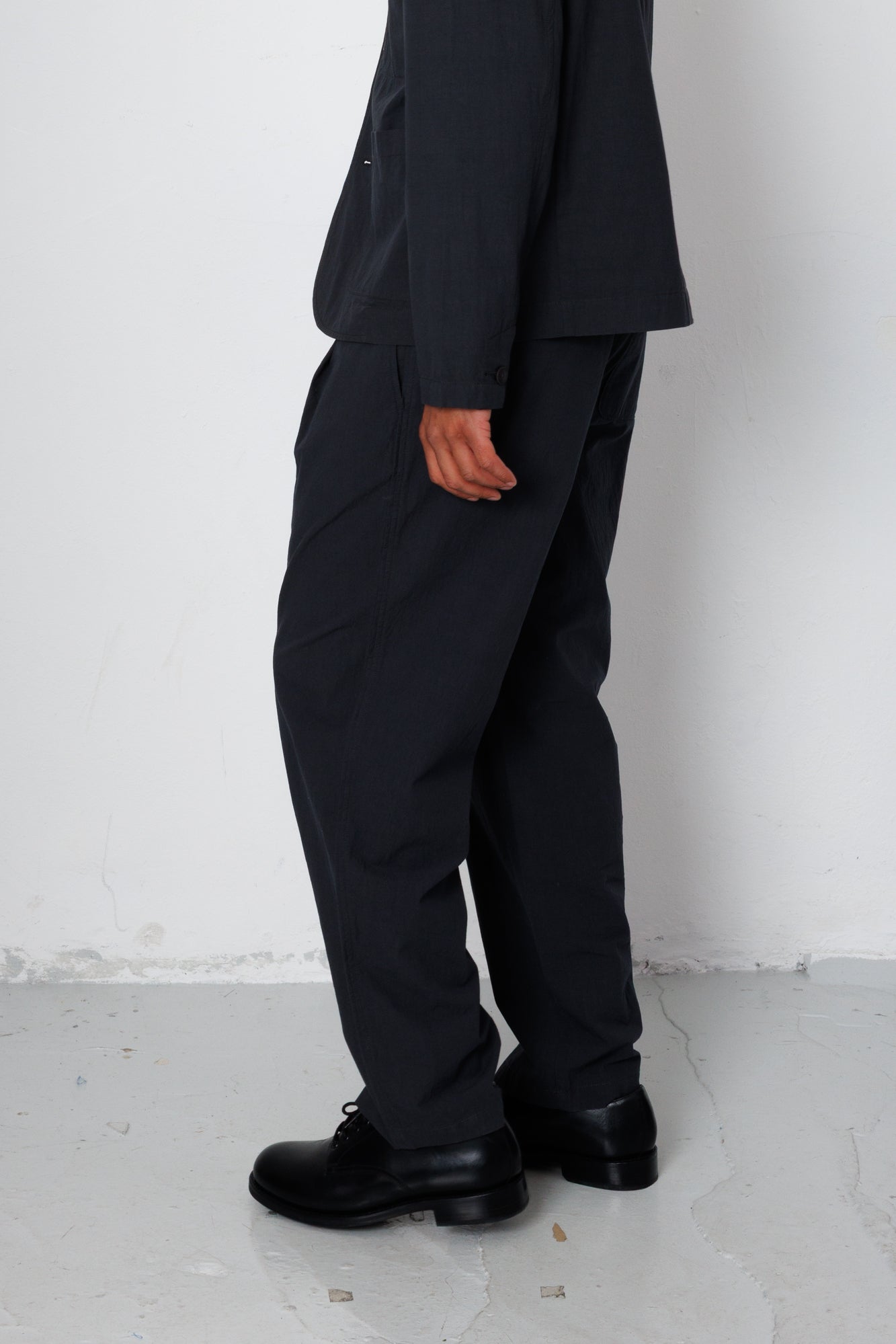 Person wearing a black suit and shoes against a white background