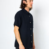 Man wearing a black short-sleeve shirt against a white background