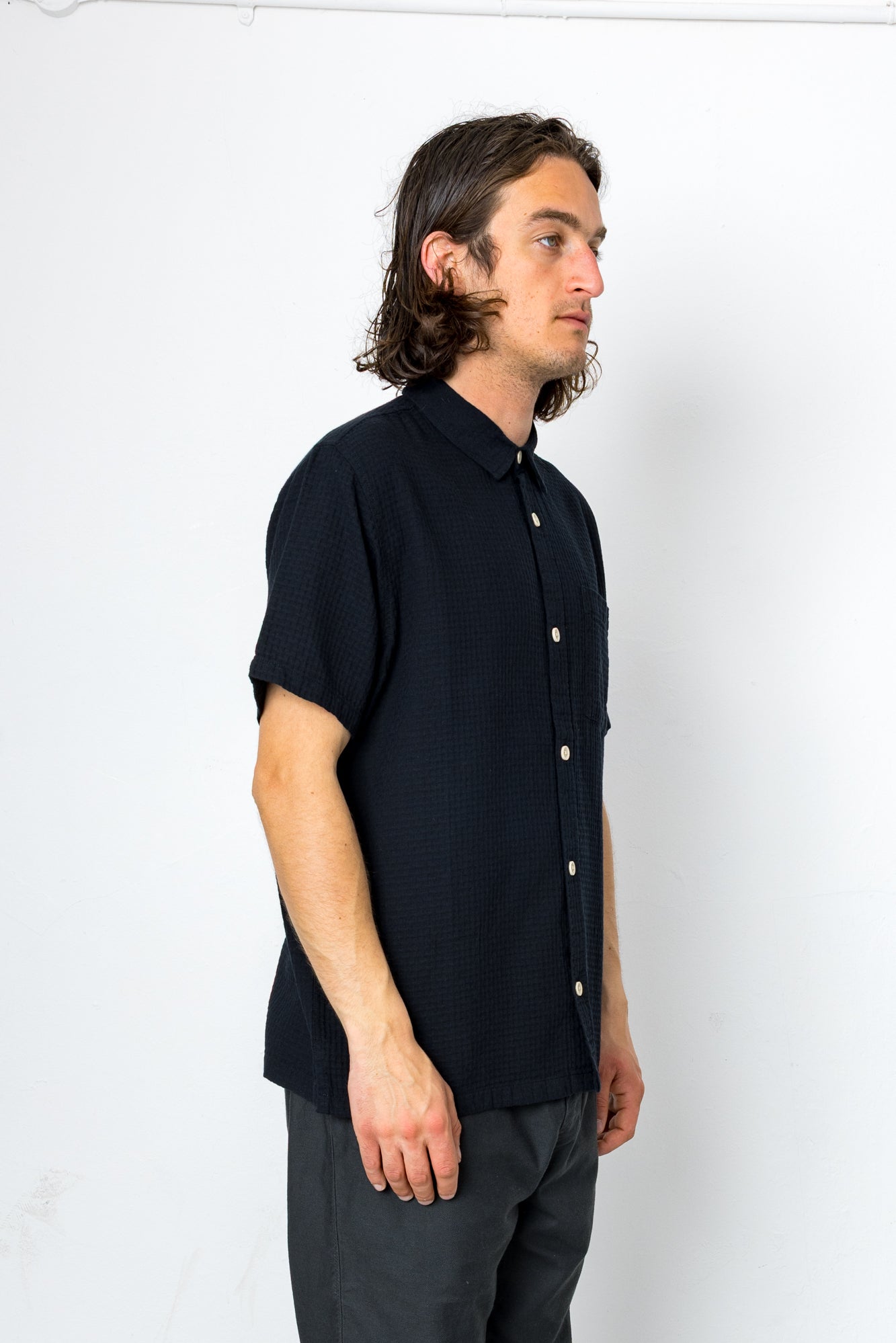 Man wearing a black short-sleeve shirt against a white background