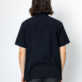 Person wearing a black shirt and dark pants against a white background