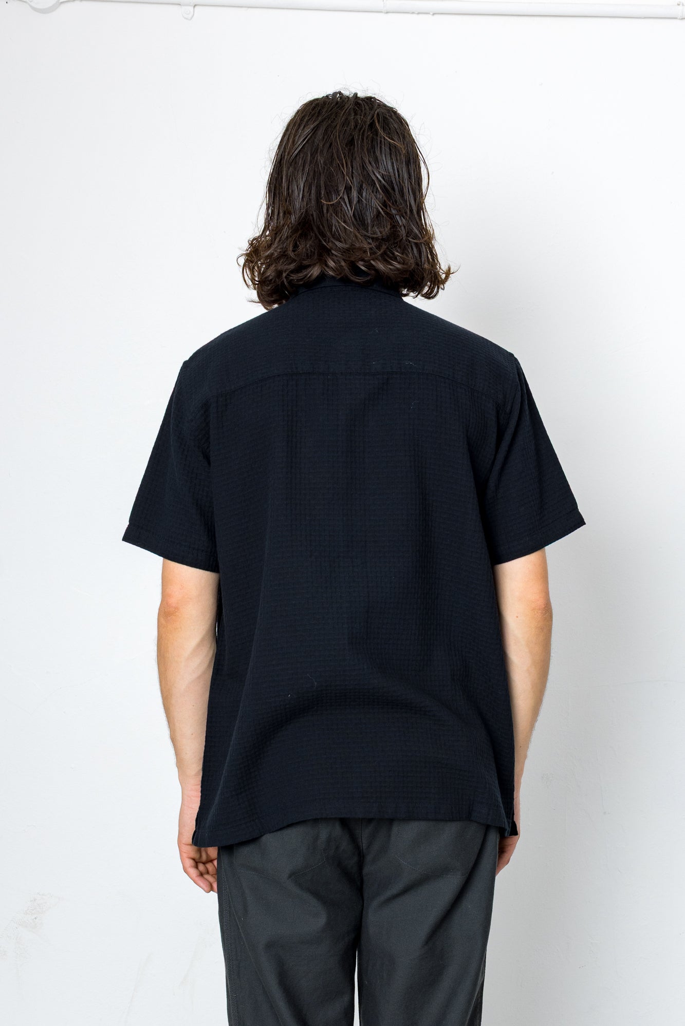 Person wearing a black shirt and dark pants against a white background