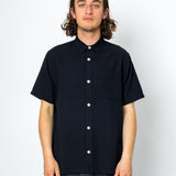Man wearing a black short-sleeve shirt with white buttons on a white background