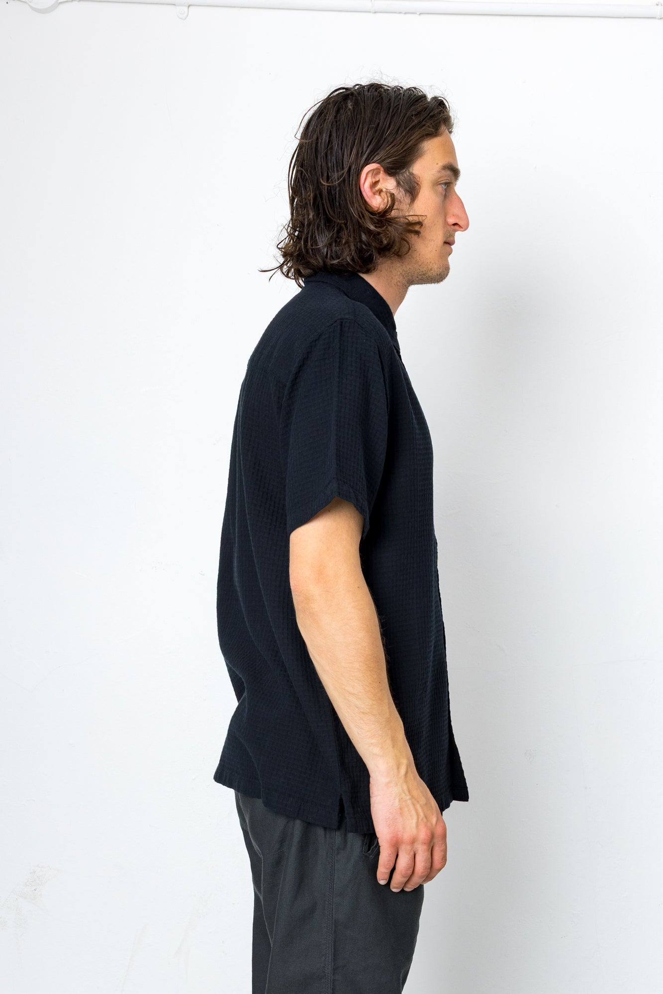 Man wearing a black shirt and gray pants against a white background
