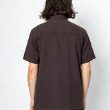 Person wearing a brown short-sleeve shirt against a white background
