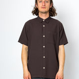 Man wearing a brown short-sleeve shirt against a white background