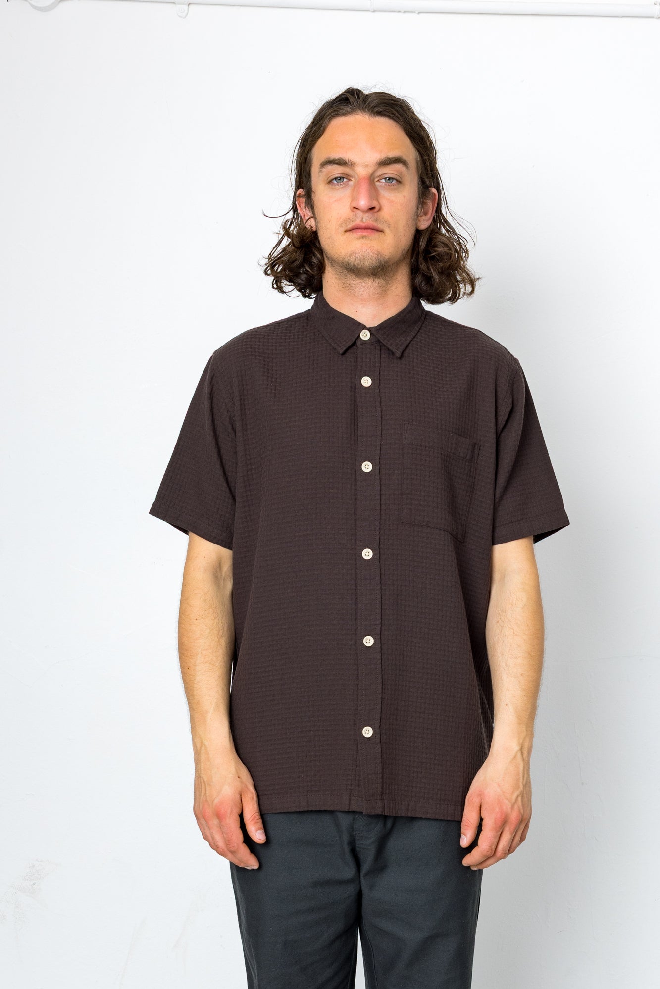 Man wearing a brown short-sleeve shirt against a white background