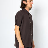Man wearing a brown short-sleeve shirt against a white background