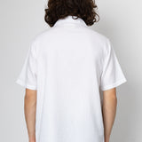Person wearing a white polo shirt with a plain background