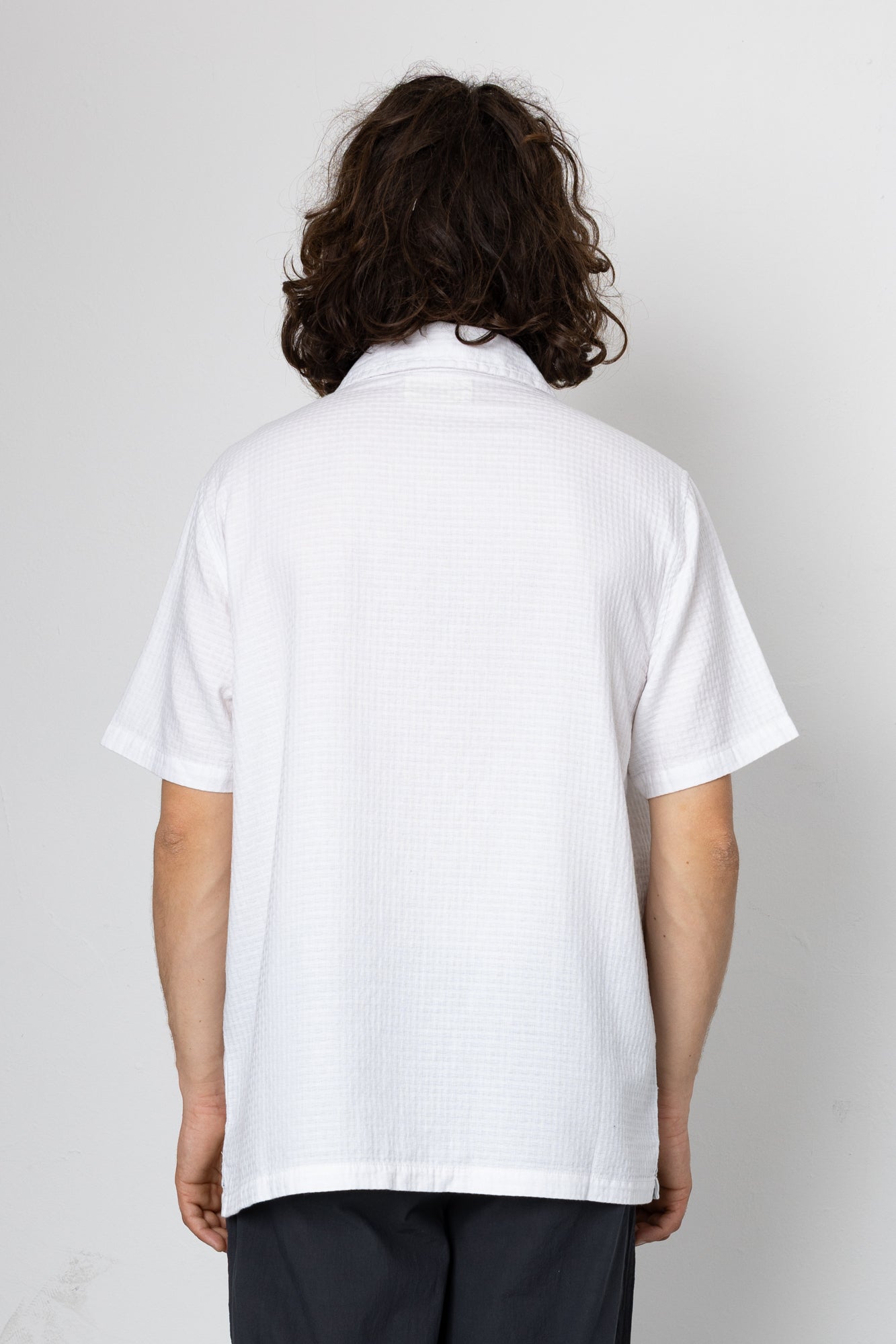 Person wearing a white polo shirt with a plain background