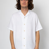 Person wearing a white short-sleeve shirt against a plain background