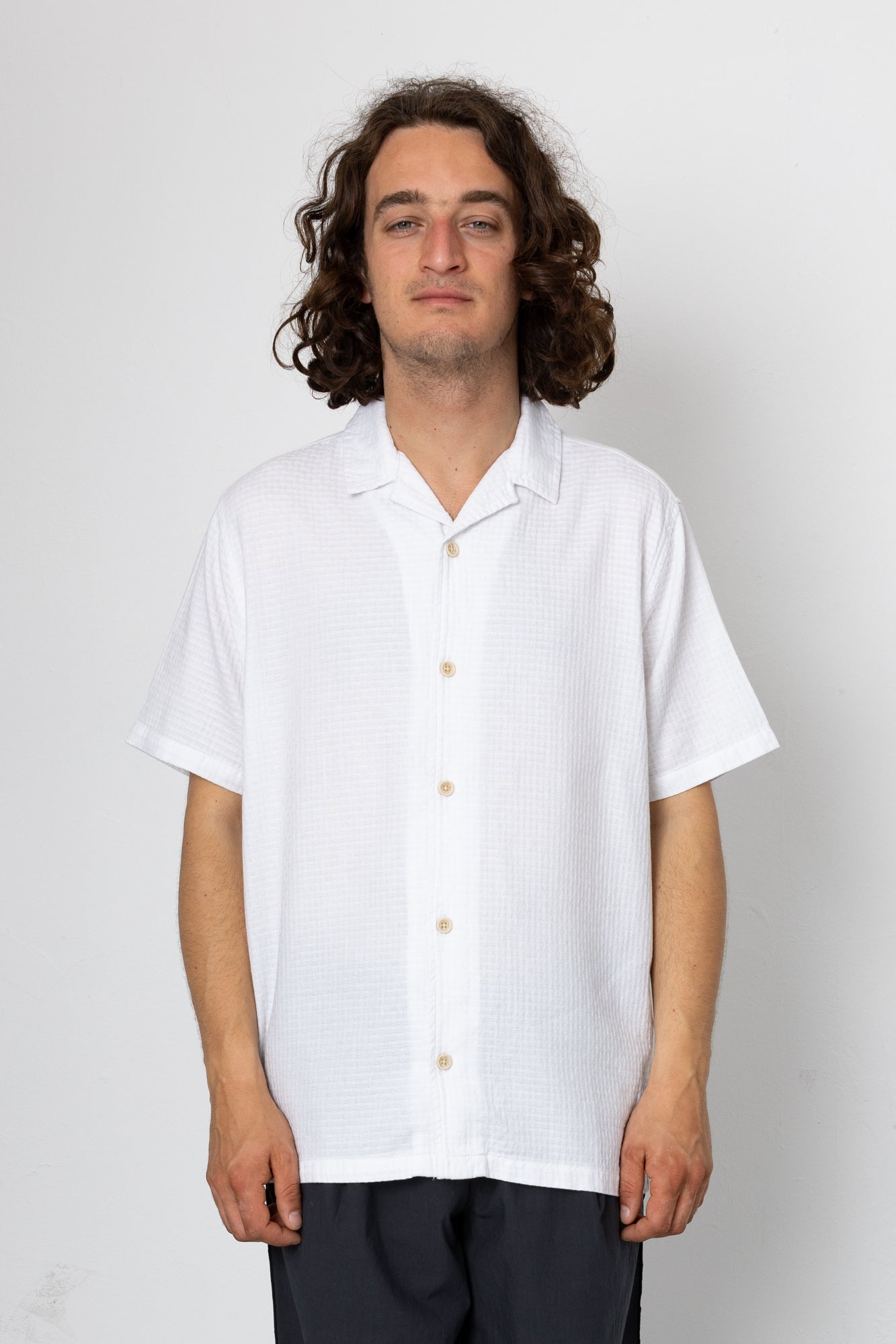 Person wearing a white short-sleeve shirt against a plain background