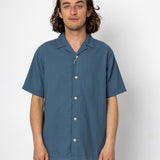 Man wearing a blue short-sleeve shirt against a white background