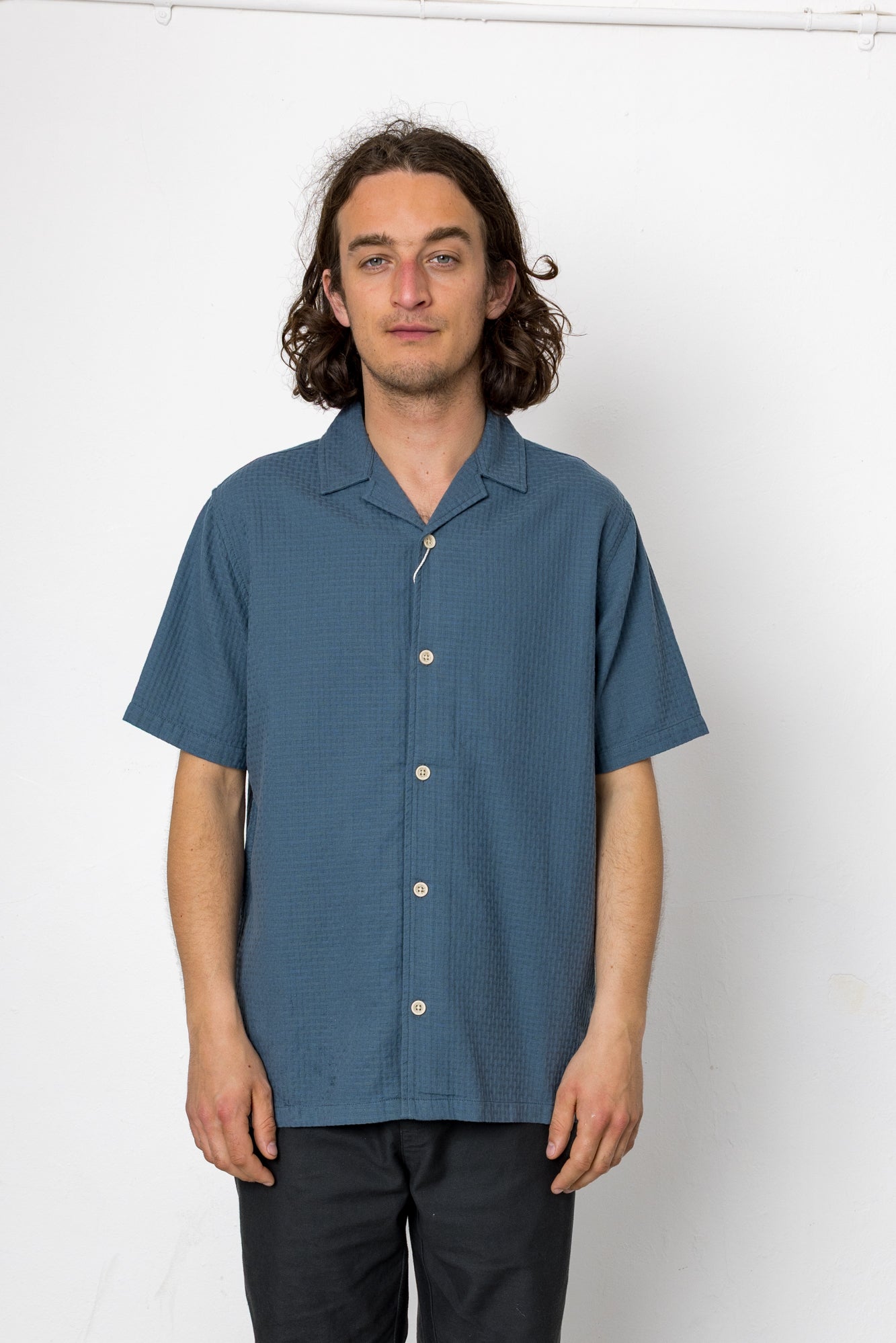 Man wearing a blue short-sleeve shirt against a white background