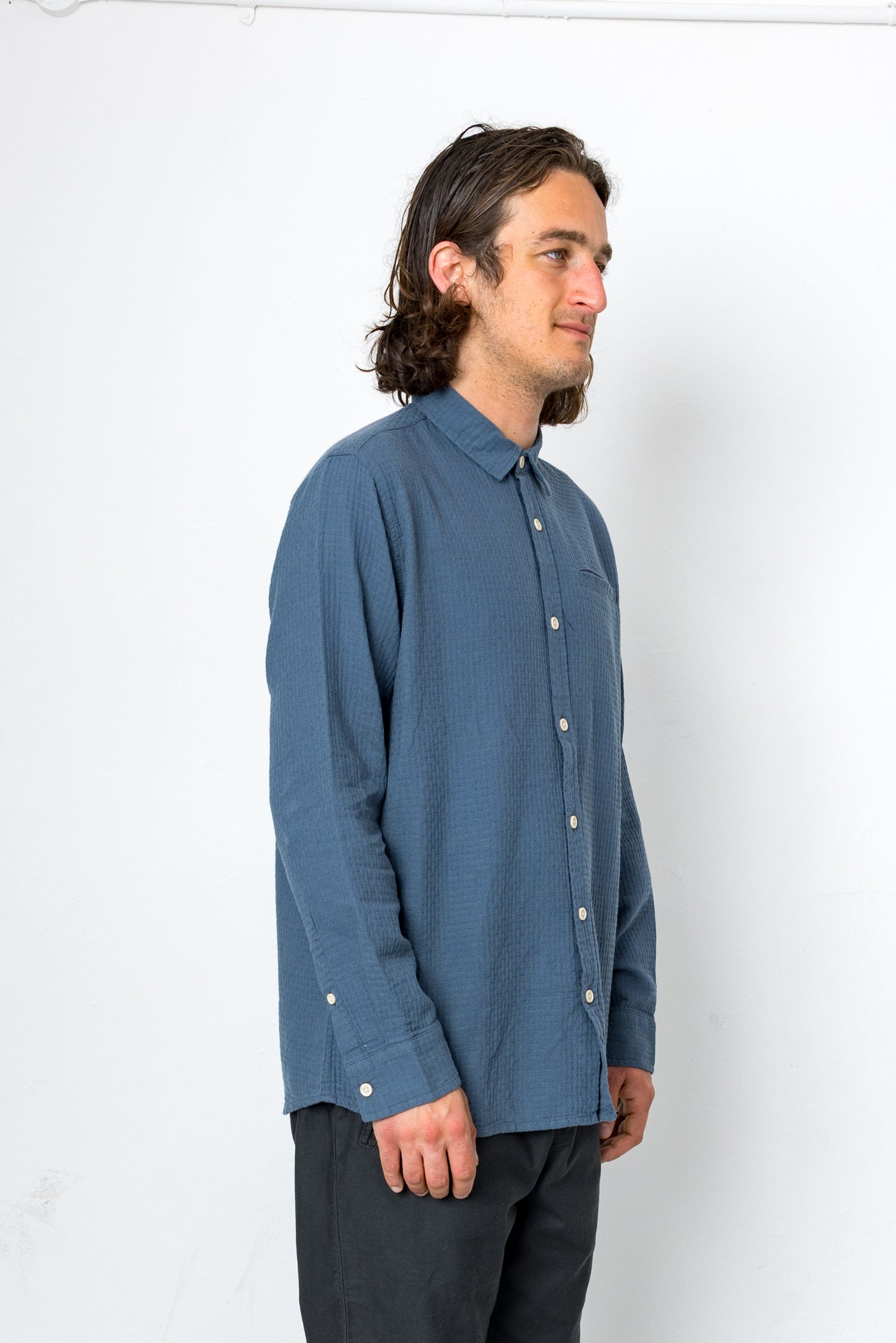 Man wearing a blue button-up shirt against a white background
