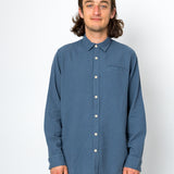 Man wearing a blue button-up shirt against a white background
