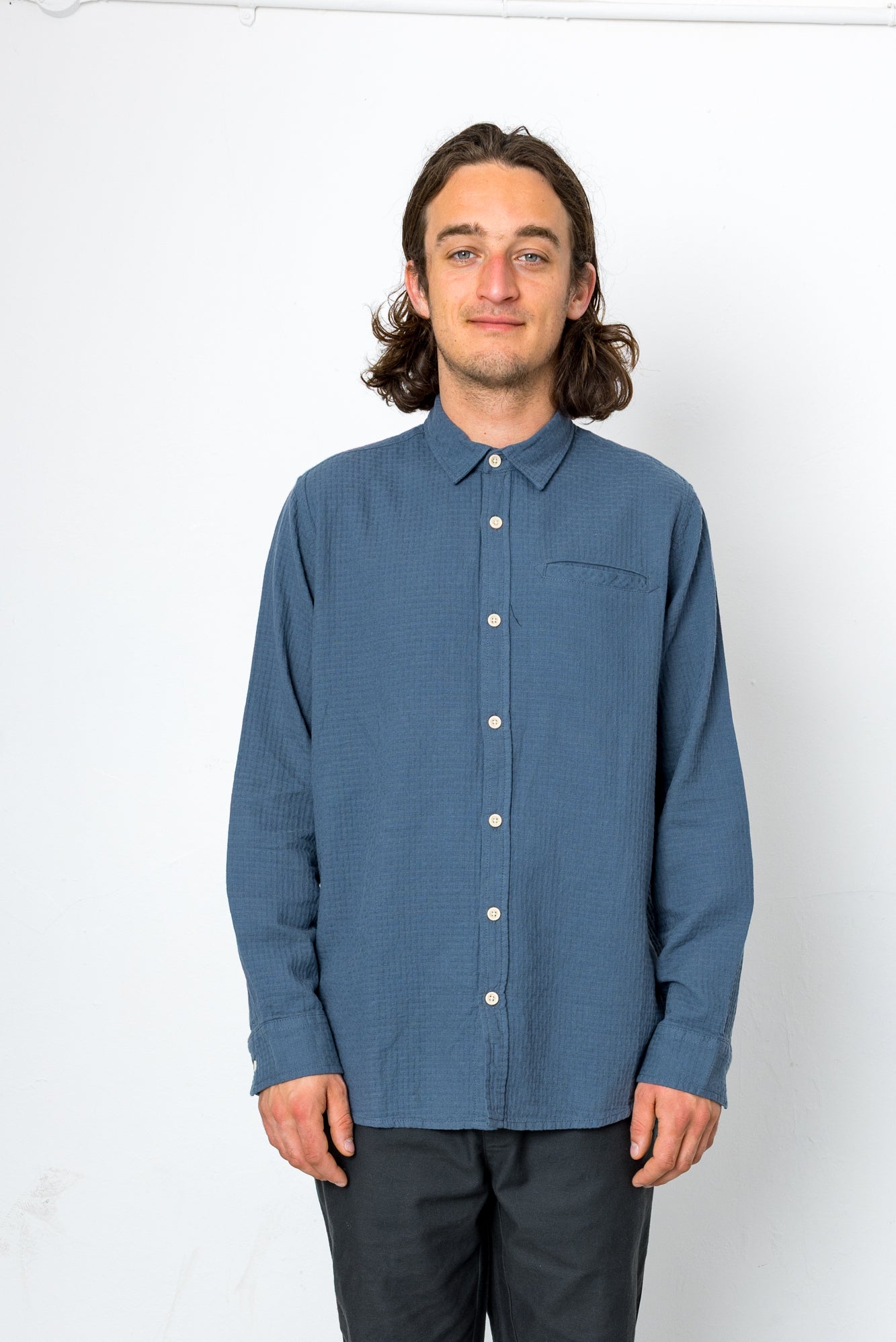 Man wearing a blue button-up shirt against a white background