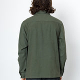 Person wearing a green shirt and dark pants against a white background