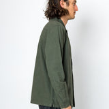 Man wearing a green jacket and dark pants against a white background