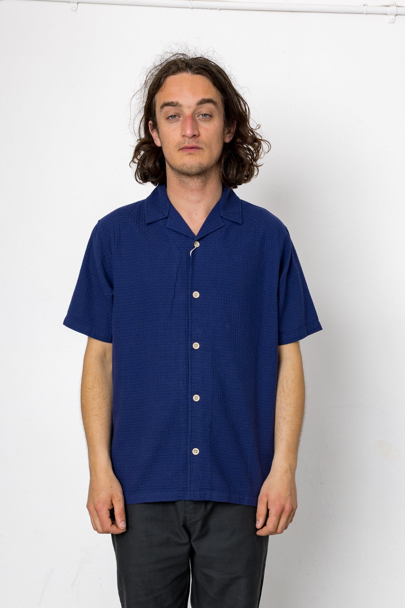 Man wearing a blue short-sleeve shirt against a white background