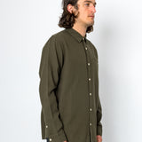 Man wearing an olive green button-up shirt against a white background