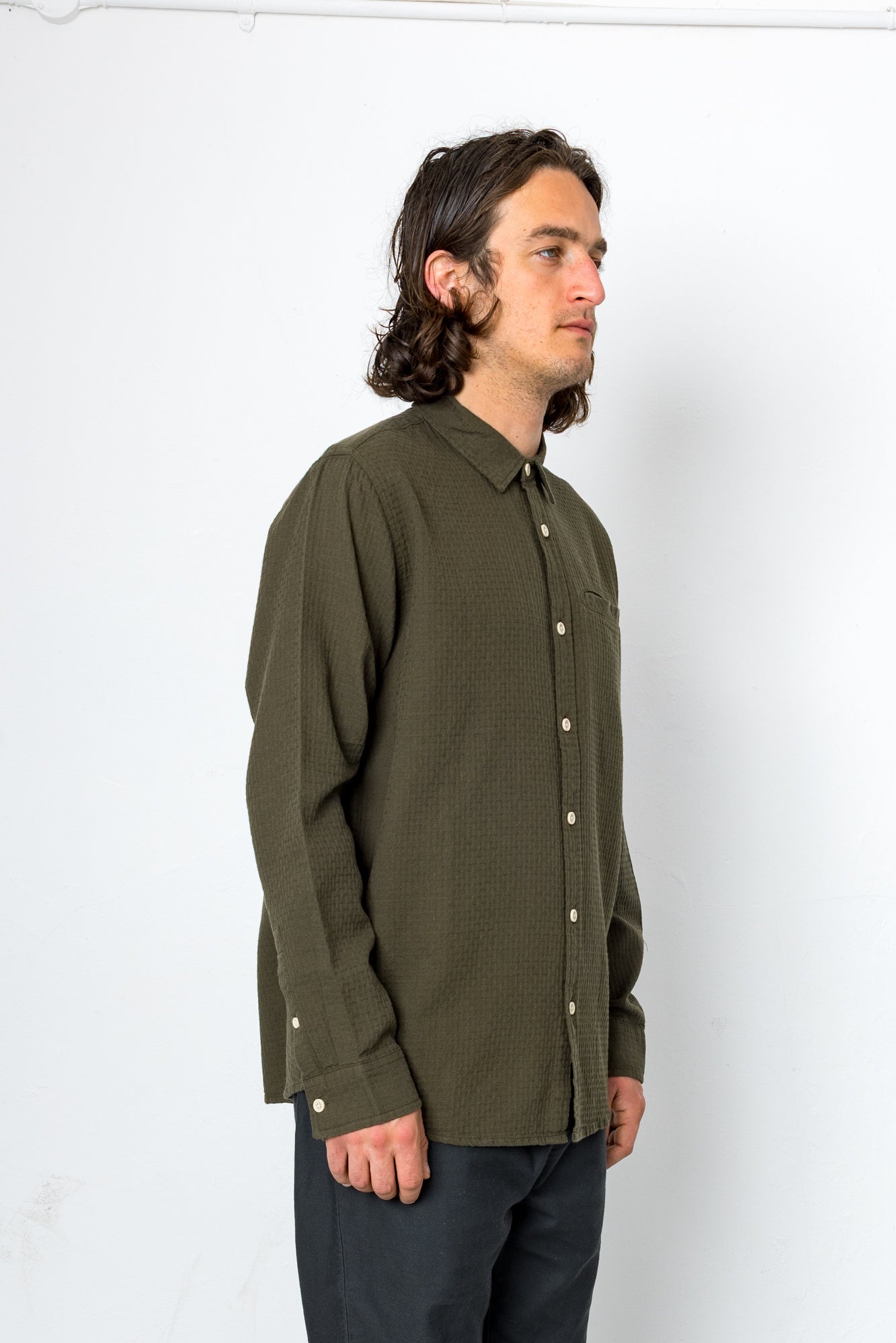 Man wearing an olive green button-up shirt against a white background