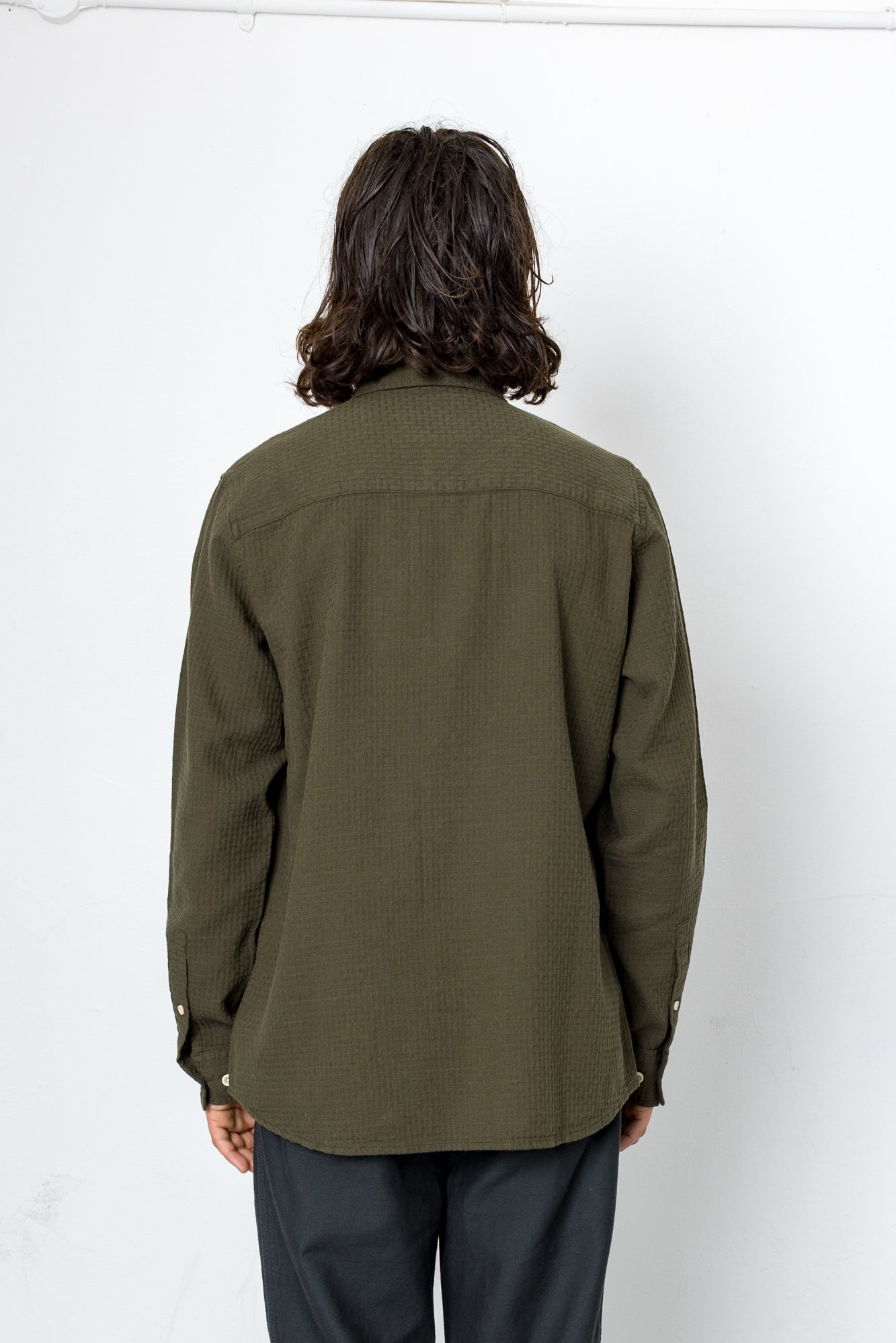 Person wearing an olive green shirt against a white background