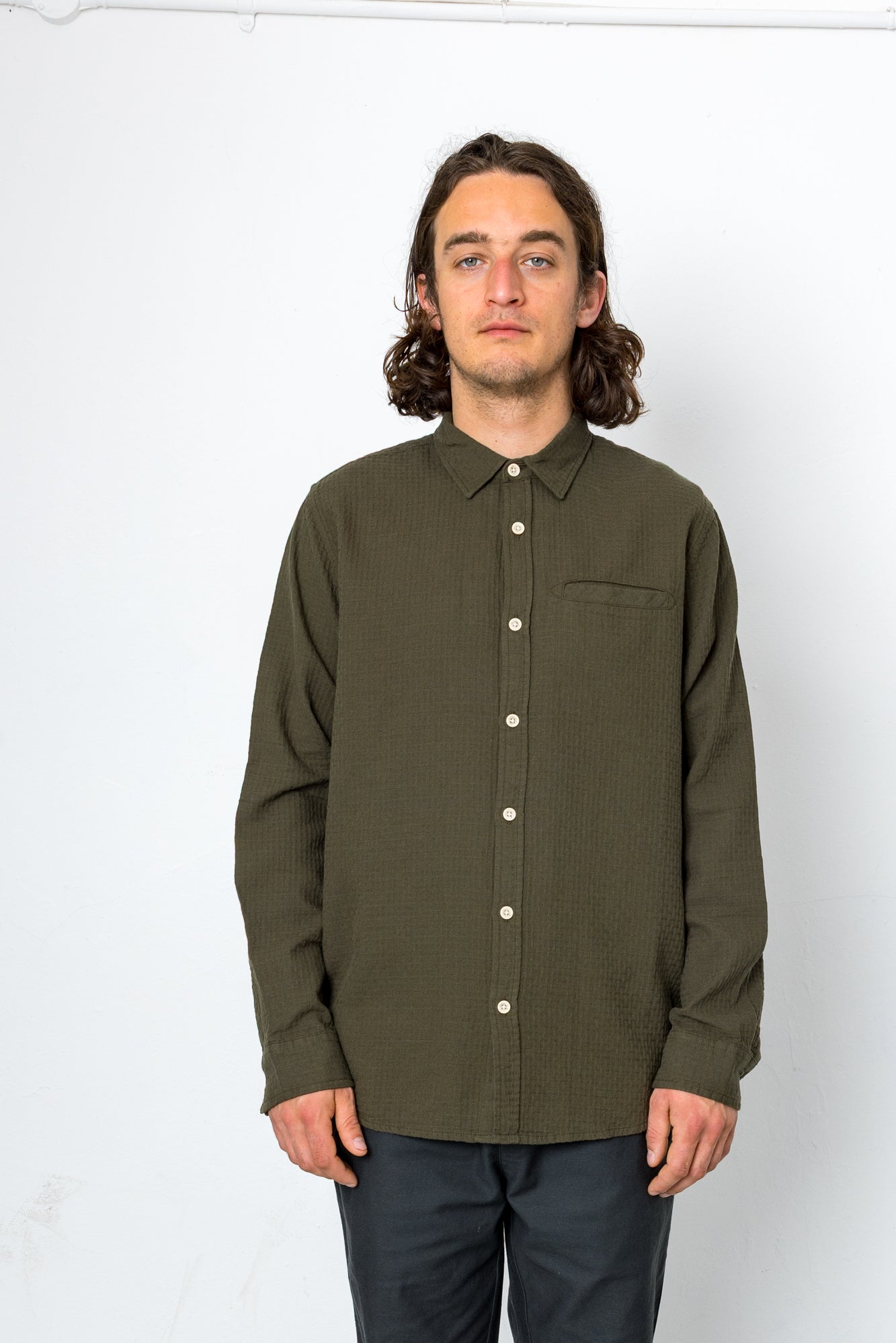 Man wearing an olive green button-up shirt against a white background