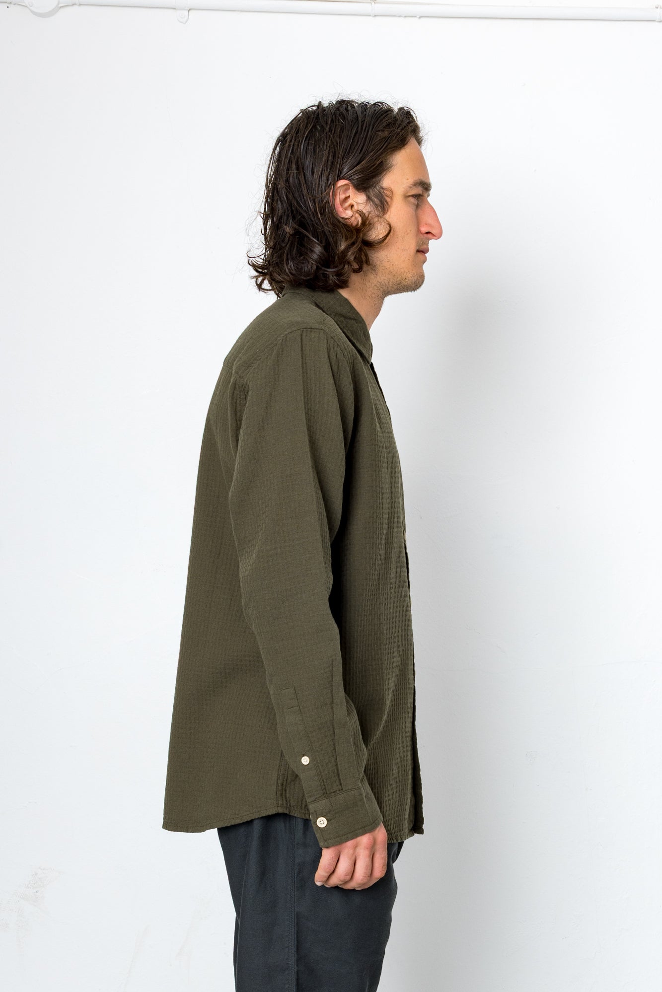 Man wearing an olive green shirt against a white background