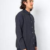Man wearing a dark gray button-up shirt and pants against a white background