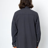Person wearing a dark gray shirt and pants against a white background