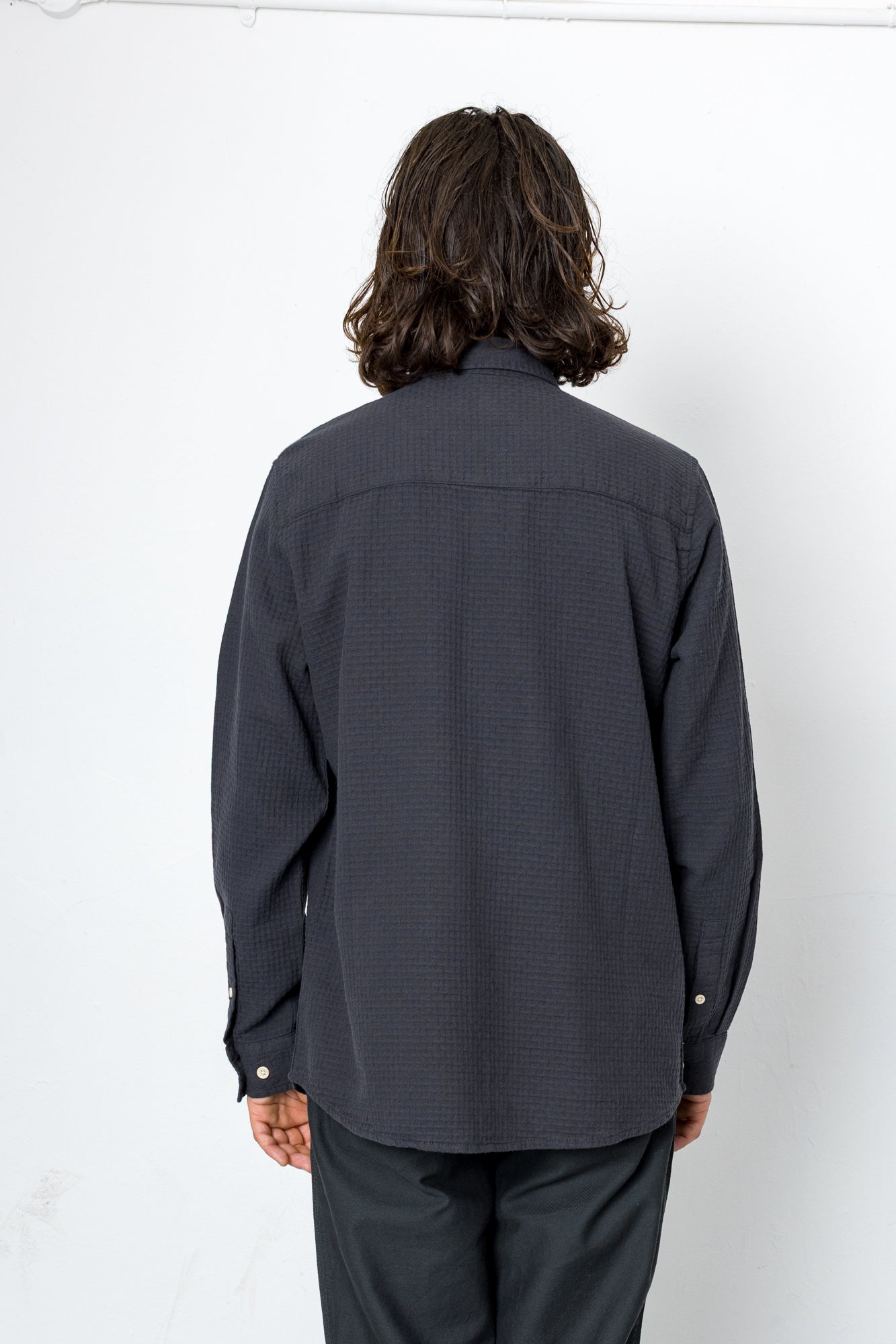 Person wearing a dark gray shirt and pants against a white background