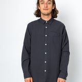Man wearing a dark button-up shirt against a white background