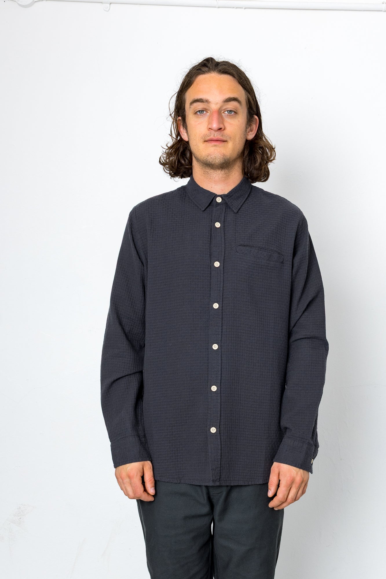Man wearing a dark button-up shirt against a white background