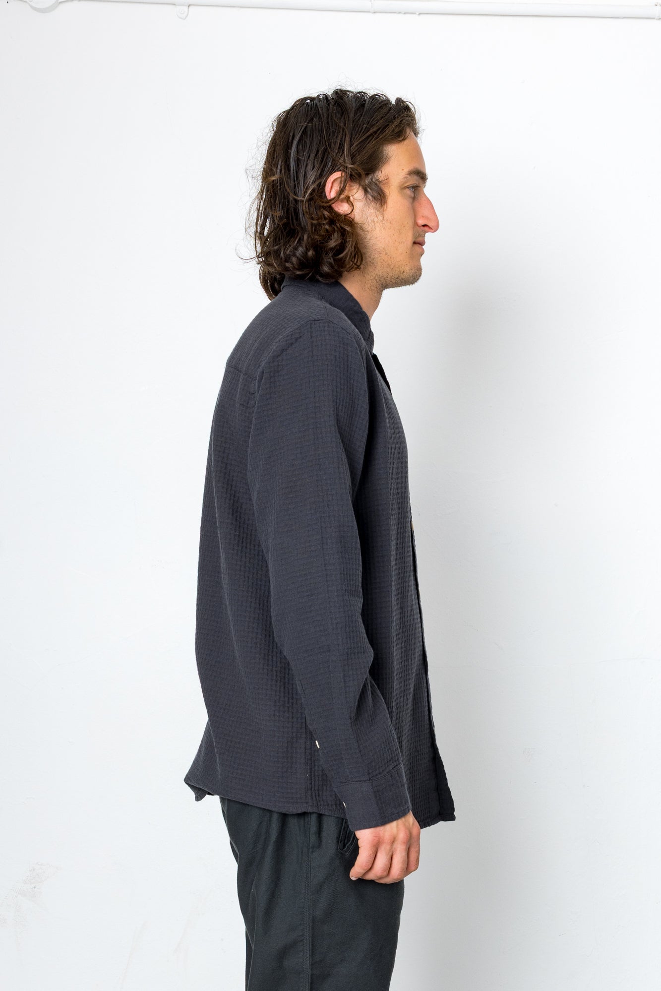 Man wearing a dark gray shirt and pants against a white background