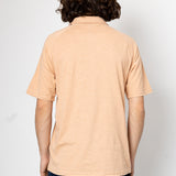 Person wearing a beige polo shirt and dark pants against a white background