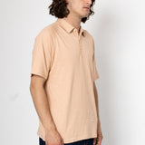 Man wearing a beige polo shirt against a white background