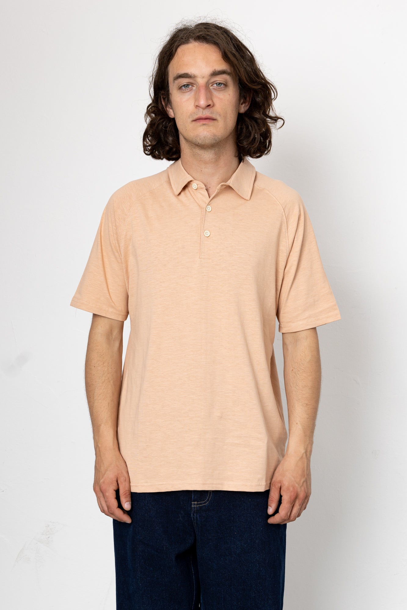 Man wearing a beige polo shirt against a white background