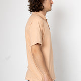 Man wearing a beige polo shirt against a white background