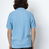 Person wearing a light blue ribbed sweater against a white background