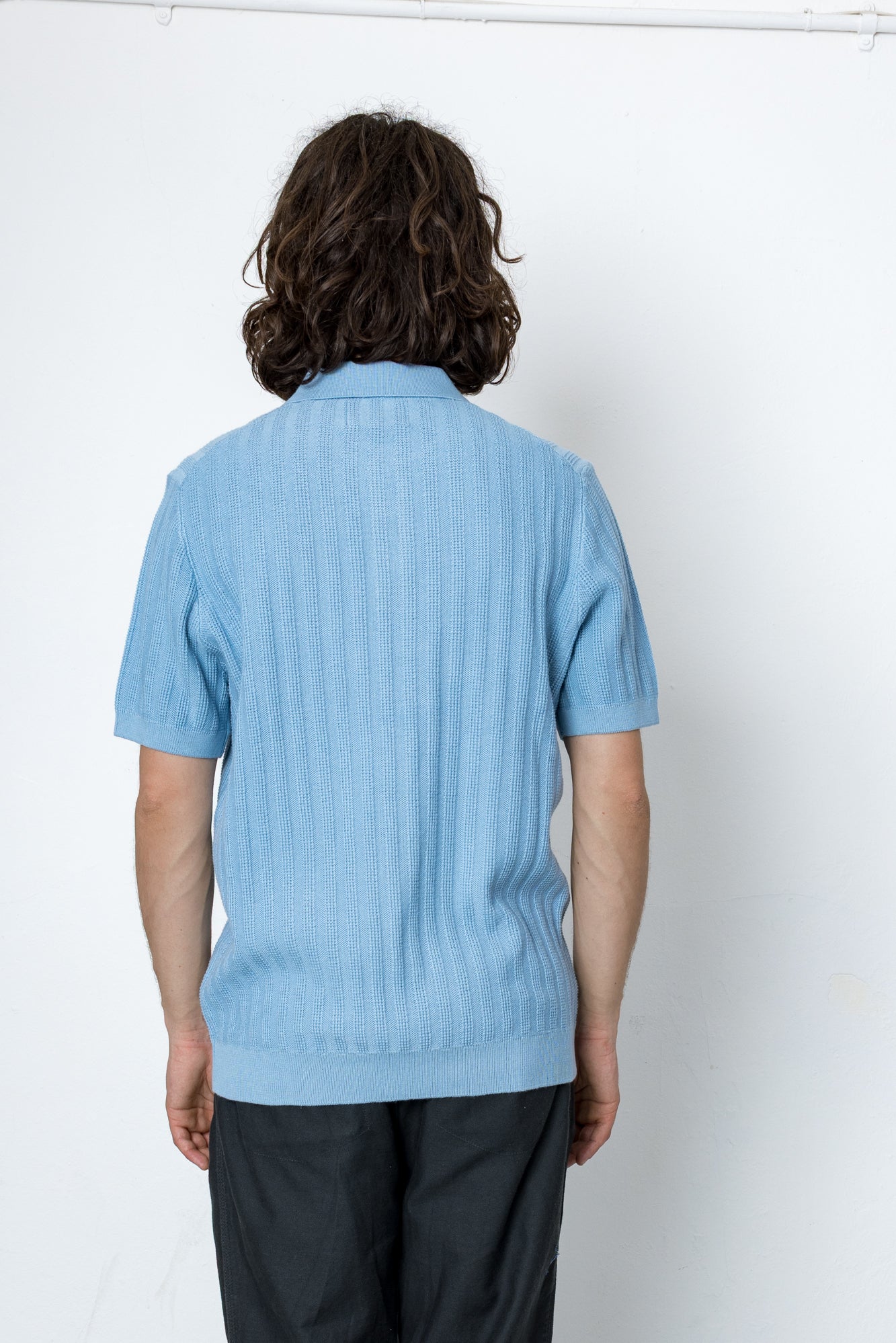 Person wearing a light blue ribbed sweater against a white background