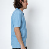 Man wearing a light blue polo shirt against a white background