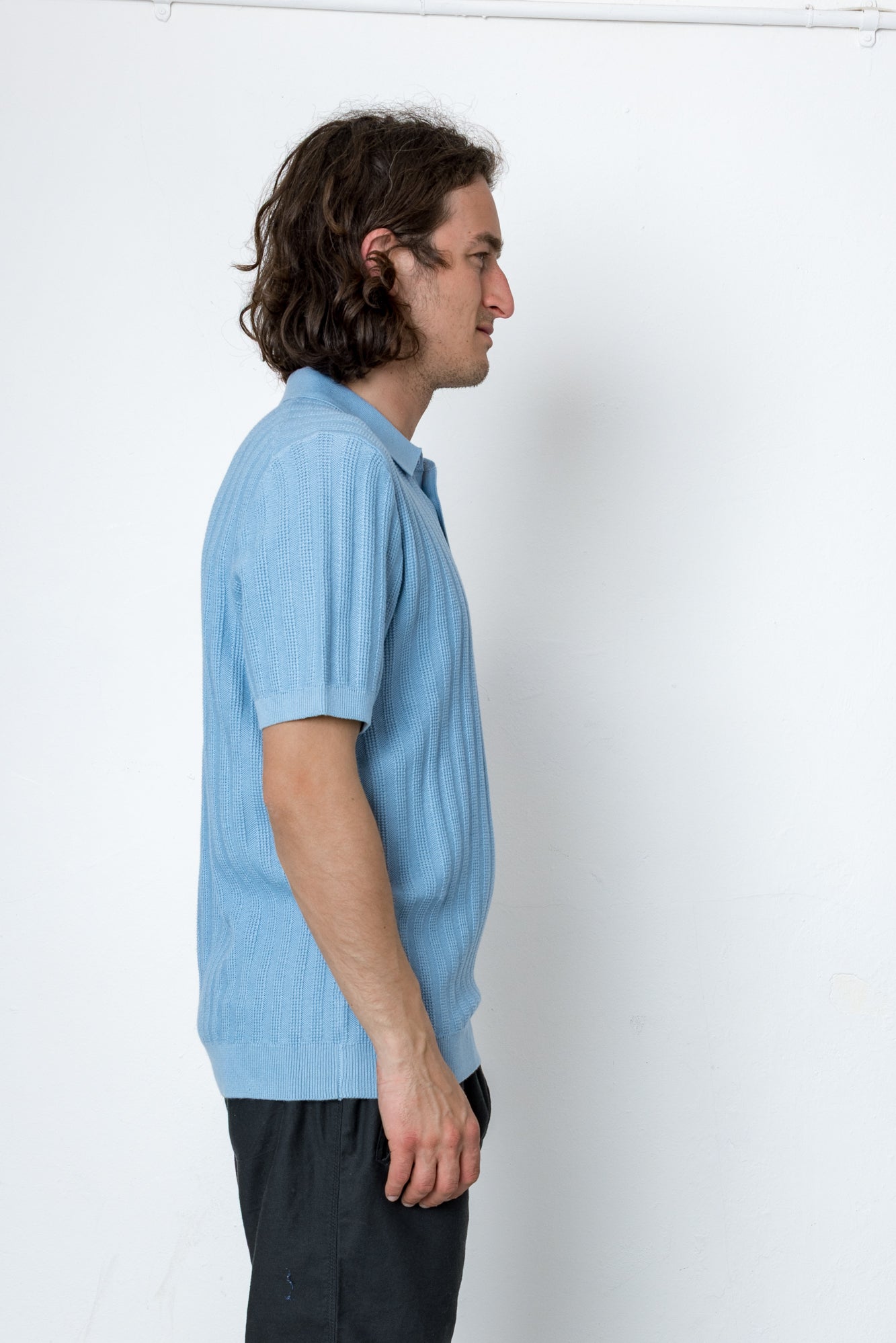 Man wearing a light blue polo shirt against a white background